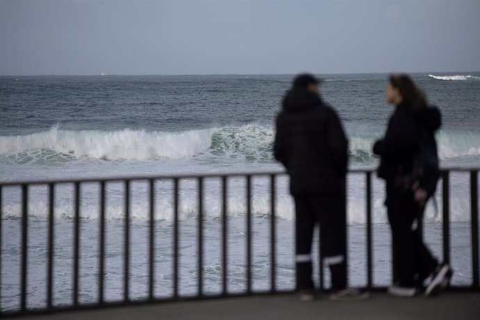 Archivo - Dos personas frente a una ola en el mar. 