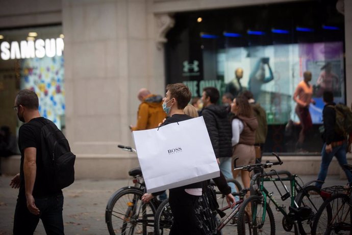 Archivo - Un joven en bicicleta camina con una bolsa por una vía de Barcelona, a 27 de diciembre de 2021, en Barcelona, Catalunya, (España). 