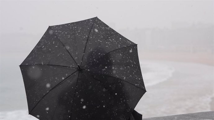 Archivo - Una persona con paraguas para refugiarse de la nieve, en la playa de Ondarreta, a 27 de febrero de 2023, en San Sebastián, Gipuzkoa, País Vasco (España).