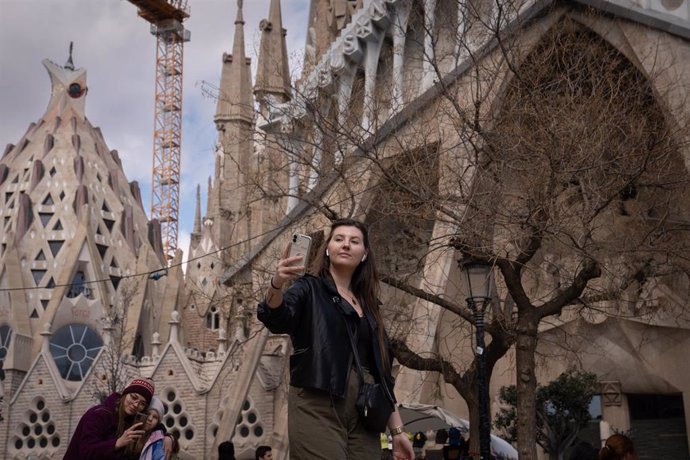 Archivo - Una turista saca una foto junto a la Sagrada Familia.