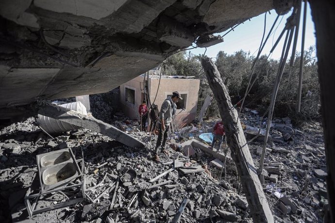 Varias personas inspeccionan los escombros de un edificio destruido en Deir el Balá, en la Franja de Gaza