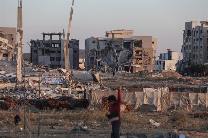 Palestinos caminan en la ciudad de Deir al Balá frente a edificios destruidos por la ofensiva de Israel contra la Franja de Gaza (archivo)