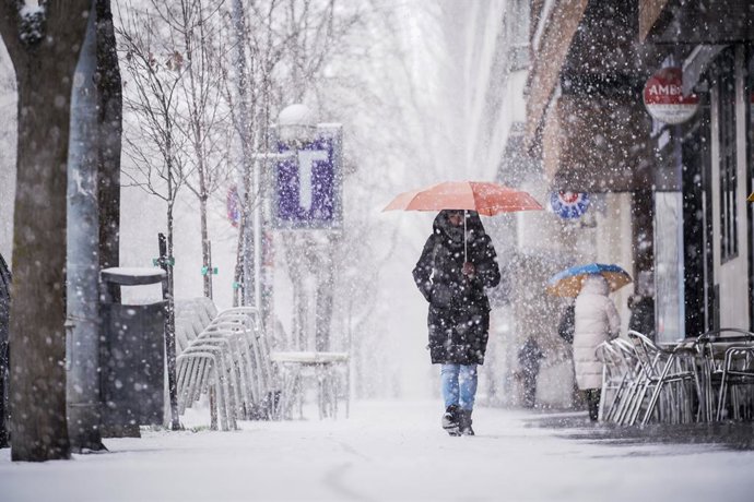 Archivo - Una persona sujeta un paraguas al caminar por una de las calles de Vitoria-Gasteiz tras la intensa nevada caída sobre la ciudad, a 27 de febrero de 2023, en Vitoria-Gasteiz, Álava, Euskadi (España). Desde las 10:00 h. de hoy ha caído una intensa
