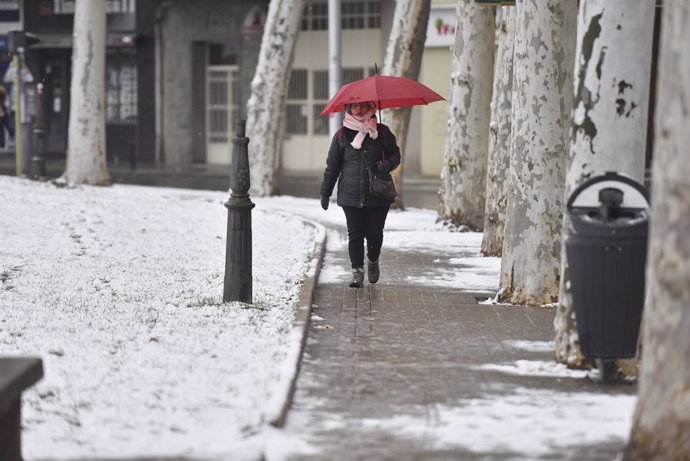 Archivo - Una mujer sujeta un paraguas mientras camina por una calle de nieve, a 10 de enero de 2024, en Jaca, Huesca, Aragón (España). La DANA ha llegado a Aragón con lluvia, frío y nieve, poniendo en alerta a los servicios de protección civil de la comu