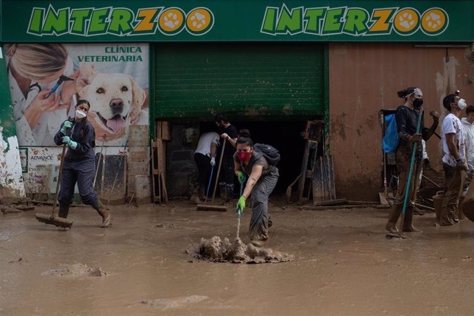 Varias personas trabajan en la limpieza de un comercio  afectado por la DANA en la Comunidad Valenciana. 