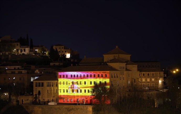 Una imagen en movimiento de la bandera de España ilumina la fachada de las Cortes de Castilla-La Mancha por el Día de la Constitución