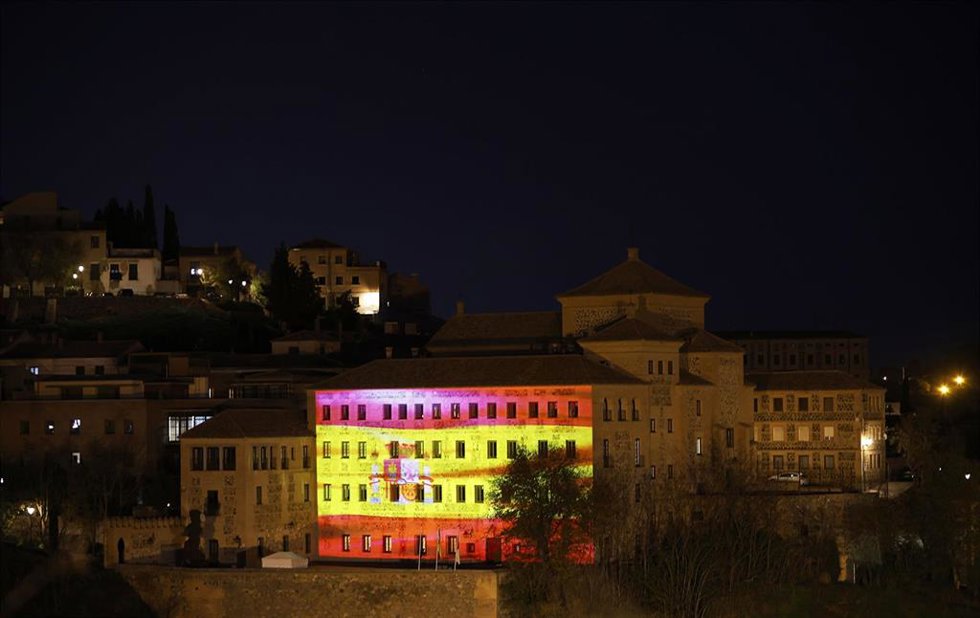Una imagen en movimiento de la bandera de España ilumina la fachada de las Cortes de Castilla-La Mancha por el Día de la Constitución