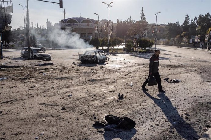 Un hombre camina ante un vehículo en llamas en la ciudad siria de Alepo