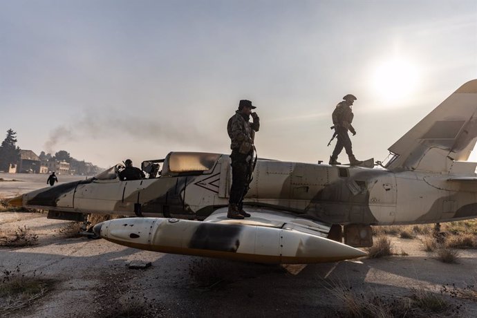 02 December 2024, Syria, Aleppo: Members of the Syrian armed opposition on top of a military aircraft after gaining control of the Nayrab military airport in the city of Aleppo. Photo: Anas Alkharboutli/dpa