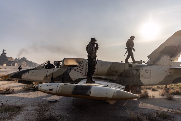 Miembros de la oposición armada siria encima de un avión militar tras hacerse con el control del aeropuerto militar de Nayrab