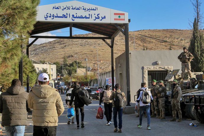 08 December 2024, Lebanon, Masnaa: Syrian refugees cross the border area of Masnaa with Syria watched by Lebanese soldiers securing the site following the fall of the Syrian regime. A rapid advance by Syrian rebel groups on the country's capital has led t