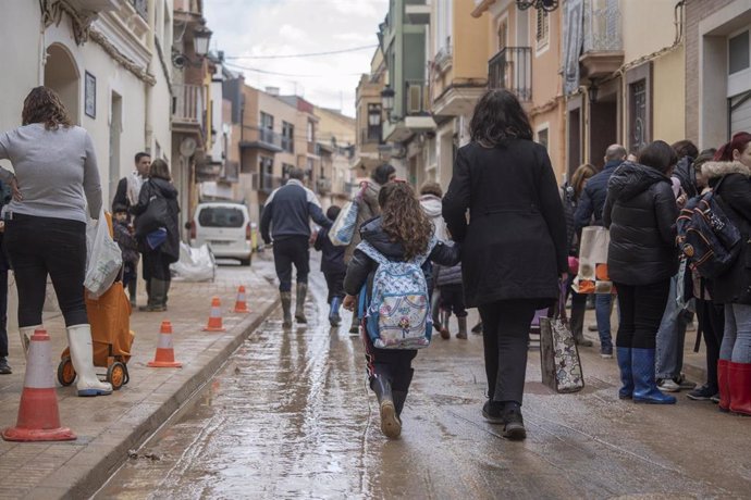 Una niña con su madre sale de un colegio de Paiporta. 