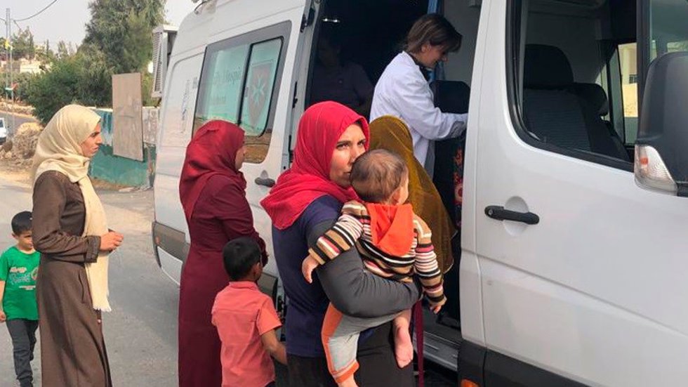 Mujeres junto a sus hijos siendo atendidas por la clínica móvil.