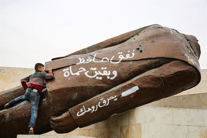 07 December 2024, Syria, Hama: A child climbs on the torn down statue of former Syrian president Hafez al-Assad in the Syrian city of Hama. Photo: Juma Mohammad/IMAGESLIVE via ZUMA Press Wire/dpa