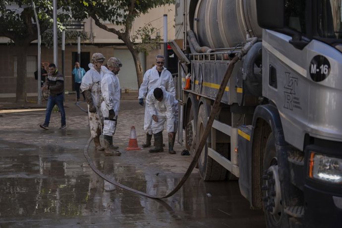Varios trabajadores durante la presentación de los nuevos dispositivos para la extracción de lodo en garajes y plantas bajas, en la Plaça País Valencià, a 27 de noviembre de 2024, en Massanassa, Valencia, Comunidad Valenciana (España). Hoy se pone en marc