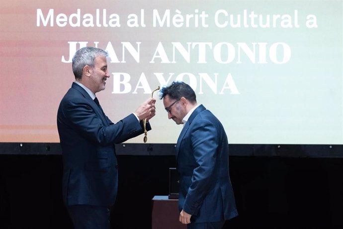 El alcalde de Barcelona, Jaume Collboni (i), entrega la Medalla al Mèrit Cultural al cineasta Juan Antonio Bayona (d), en el Ayuntamiento de Barcelona, a 10 de diciembre de 2024, en Barcelona, Catalunya (España). El pleno del Ayuntamiento de Barcelona apr