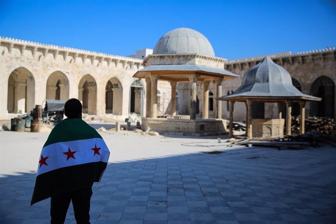 Un ciudadano despliega la bandera de la oposición al régimen de Bashar Al Assad en Alepo, Siria