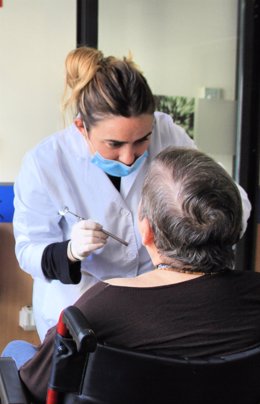 Una odontóloga atiende a una mujer en silla de ruedas.