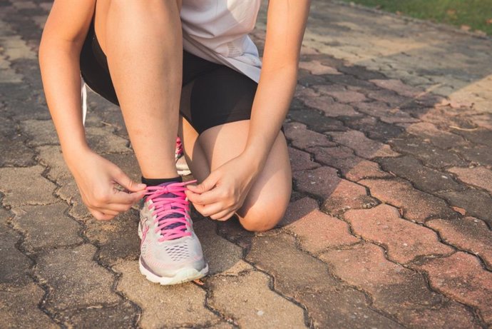 Una persona atándose los cordones de sus deportivas.