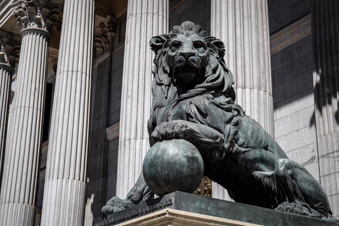 Archivo - Uno de los emblemáticos leones que se encuentran delante de la fachada del Congreso de los Diputados en la Plaza de las Cortes de Madrid.