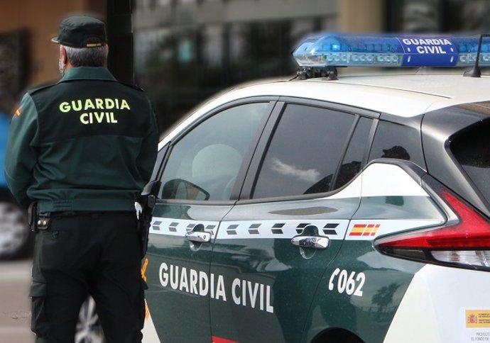 Archivo - Un agente de la Guardia Civil junto a un vehículo del cuerpo.