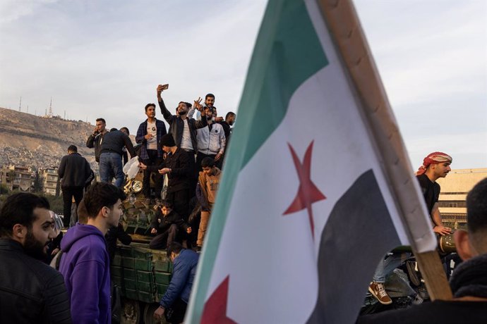 December 9, 2024, Damascus, Syria: People celebrate while standing on an abandoned Syrian army tank on December 9, 2024 at Umayyad Square at Damascus, Syria. Syrians celebrated after President Bashar al-AssadĂ•s regime collapsed by shooting guns into the 