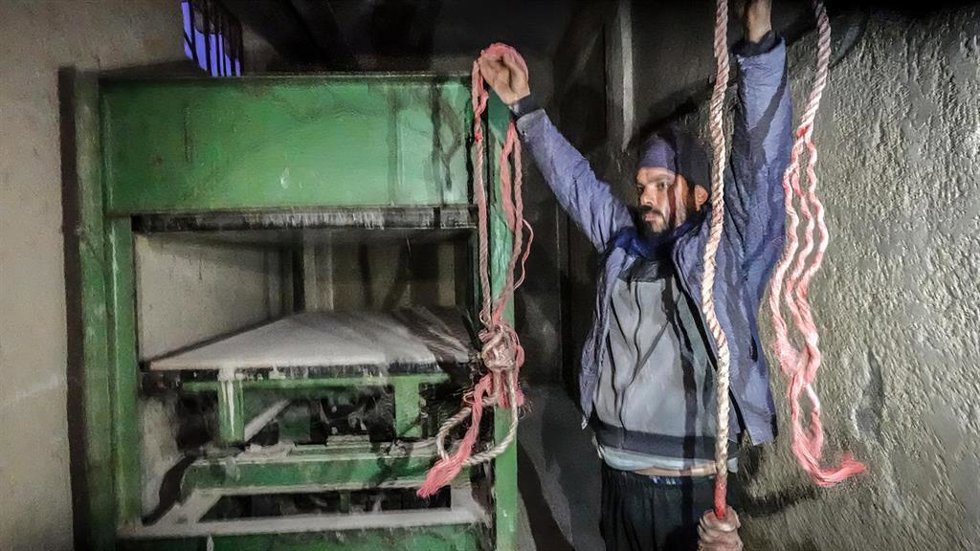 Un hombre sostiene sogas frente a una máquina conocida como "compresor" y que se cree que sirve para torturar a los presos en Sednaya (Siria)