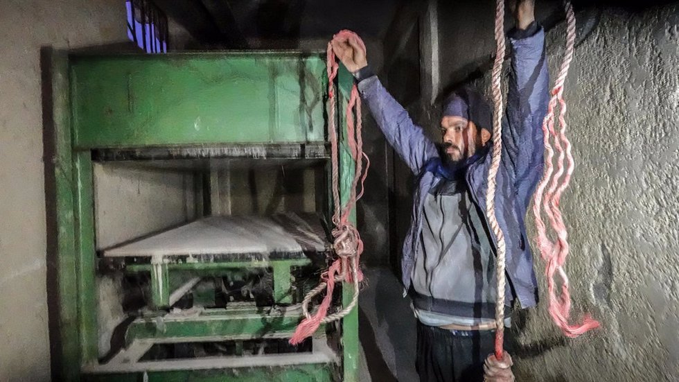 Un hombre sostiene sogas frente a una máquina conocida como "compresor" y que se cree que sirve para torturar a los presos en Sednaya (Siria)