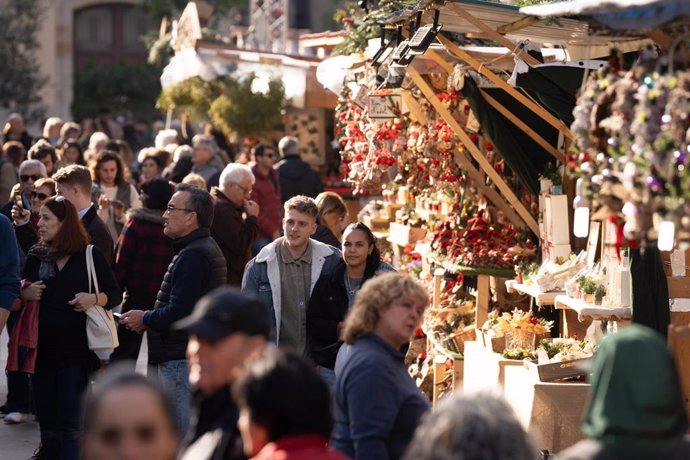 Varias personas observan el ambiente navideño en la Fira de Santa Llúcia de Barcelona