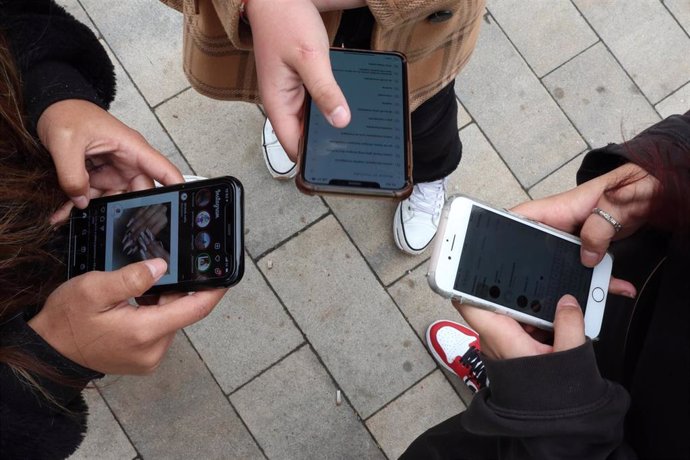 Archivo - Jóvenes utilizando sus teléfonos móviles