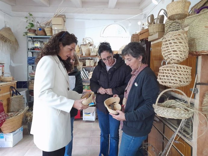 Ronte Alonso Pereda (d) muestra algunos de los productos que realiza con esparto a la delegada y la alcaldesa.