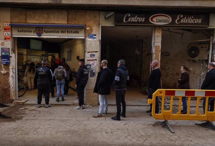 Varias personas hacen cola en una administración de lotería de Paiporta, a 13 de diciembre de 2024, tras la dana.