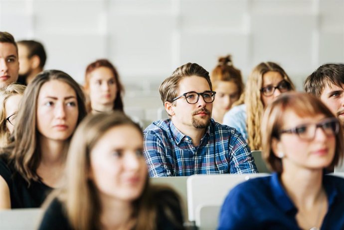 Archivo - A group of young university students concentrating carefully on their professor during a lecture.