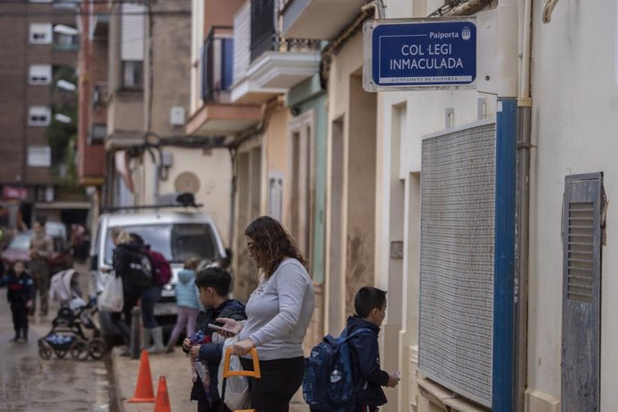 Una mare amb dos xiquets a l'eixida del col·legi 'La Inmaculada', el primer a obrir després de la dana