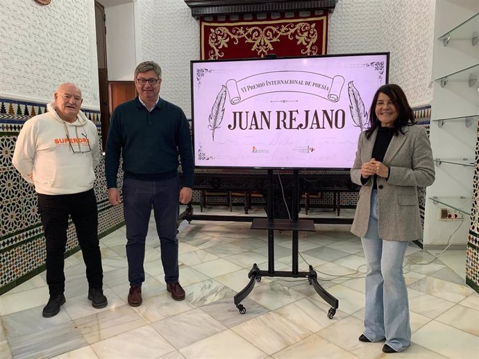 El alcalde de Puente Genil, Sergio Velasco (centro), junto al cartel del certamen de Poesía Juan Rejano.