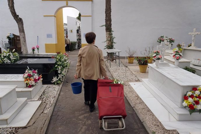 Archivo - Una persona visita y arregla una tumba en el cementerio de la barriada de El Palo en el Día de Todos los Santos.