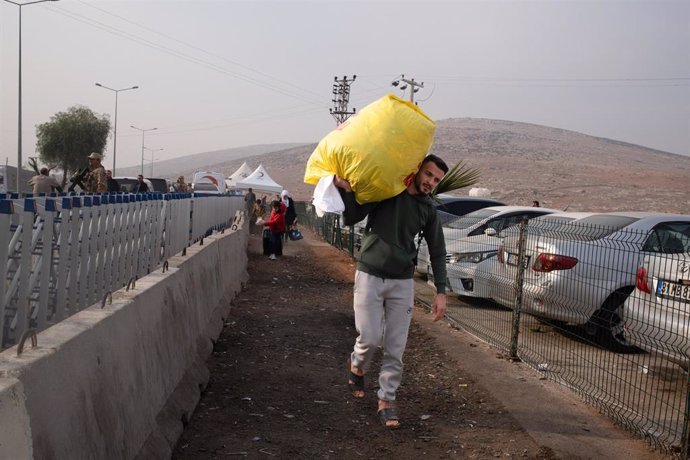 Un refugiado sirio carga sus pertenencias en la frontera con Turquía