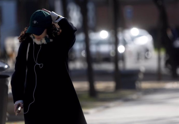 Una mujer abrigada con bufanda y gorro pasea por Madrid