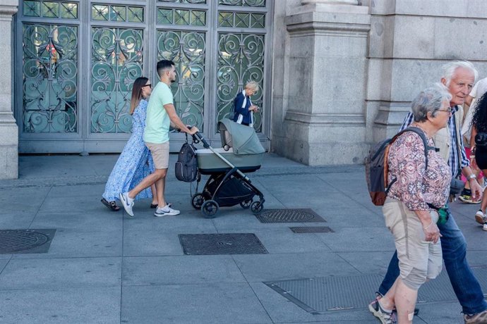 Archivo - Dos personas pasean con un carrito de bebé.