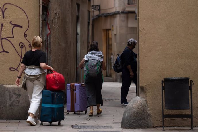 Archivo - Varios turistas con maletas en el centro de Barcelona