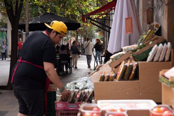 Archivo - Un dependiente coloca fruta en un estand.