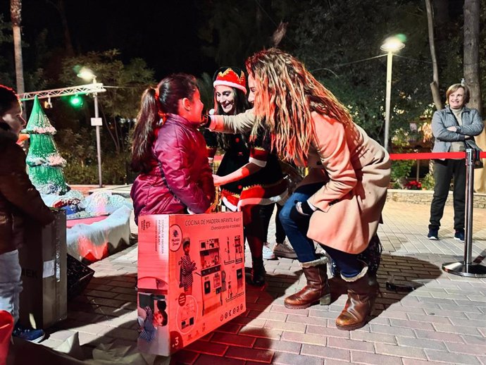 Una niña recoge su regalo de la Estrella de los Deseos en presencia de la alcaldesa