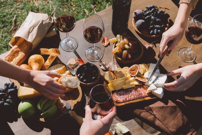 Archivo - Gente comiendo y bebiendo: higos, queso curado, salchichón y vino tinto