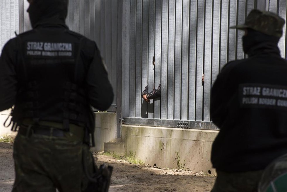 Archivo - Guardia fronterizos de Polonia en la valla que separa el país de Bielorrusia, mientras migrantes se apostan del otro lado de la frontera