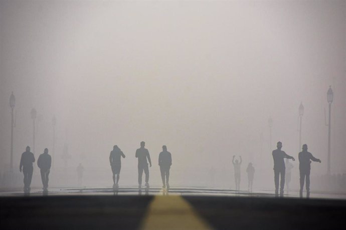 Archivo - Imagen de archivo de ciudadanos indios caminando por la calle bajo una nube de niebla contaminante