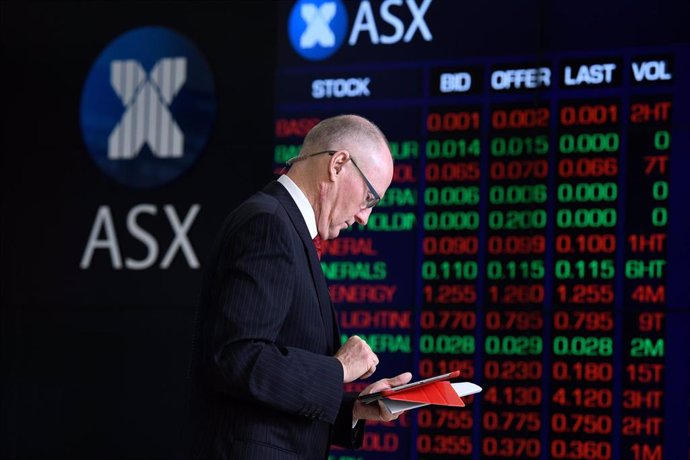 Archivo - A journalist checks his iPad in front of the digital market boards at the Australian Stock Exchange (ASX) in Sydney, Friday, March 13, 2020.