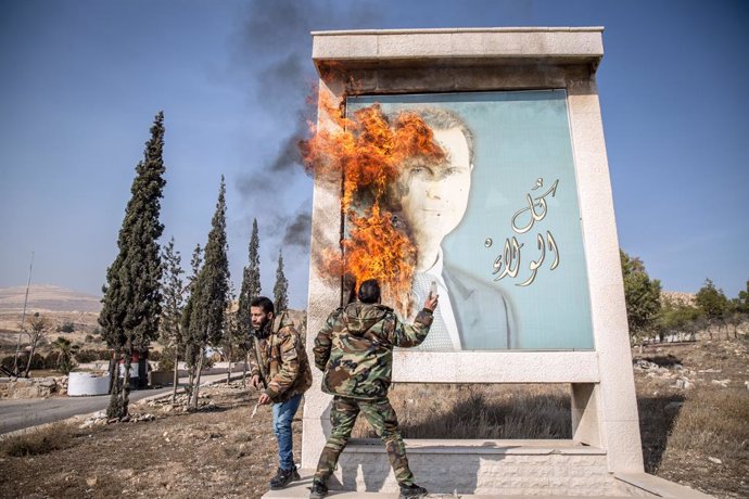 FILED - 10 December 2024, Syria, Damscus: A man burns a picture of Bashar al-Assad close to Syria's border with Lebanon. Rebels launched a shock offensive across Syria in late November, ousting al-Assad and ending more than half a century of the Assad fam