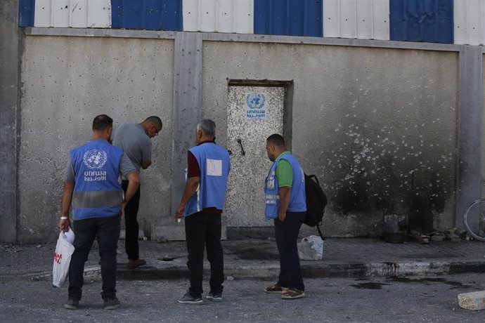 Archivo - Trabajadores de la Agencia de Naciones Unidas para los Refugiados de Palestina en Oriente Próximo (UNRWA) frente a un almacén del organismo atacado por Israel en el campamento de refugiados de Maghazi, situado en la Franja de Gaza (archivo)