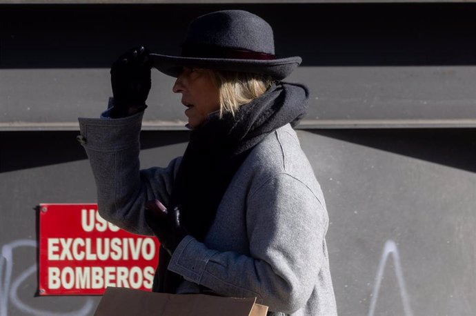 Una mujer abrigada con bufanda y gorro pasea por Madrid