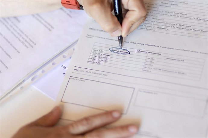 Archivo - Una mujer señala el valor de mercado de una escritura de compraventa de una hipoteca, en Madrid (España)